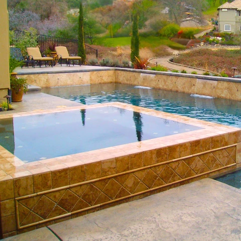 luxury infinity edge hot tub with spillover to swimming pool